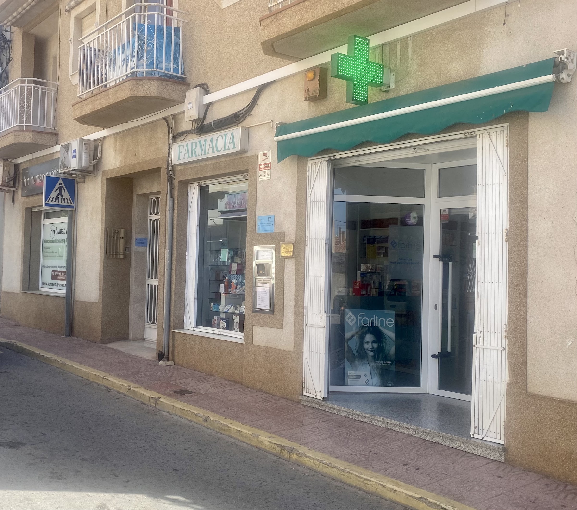 Fachada de la Farmacia José Luis Pérez con su cruz verde, en C. Cartagena 92, Puerto de Mazarrón